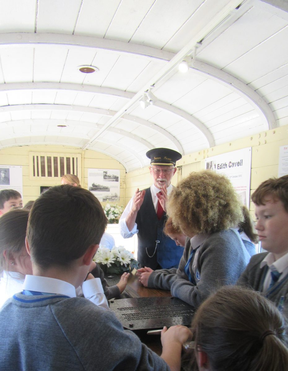 Station master giving talk to children inside steam train carriage