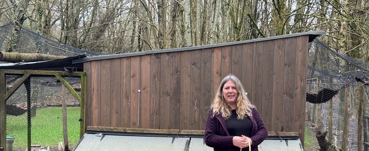A woman holding a basket, standing in front of a shed